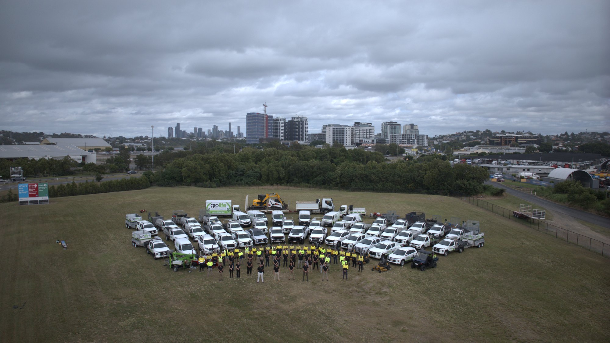 The full Grolife team and fleet — aerial shot with Brisbane skyline